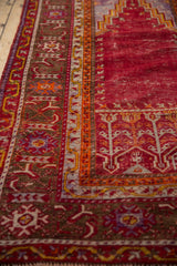 Close-up of the vintage Ghiordes rug's geometric borders in saffron yellow, brown, and cherry red.