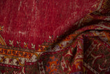 Close view of a vintage Ghiordes rug's texture, showing knot heads and the floral border.