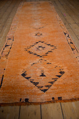 Low angle view of a distressed vintage Kurd runner in pale tangerine and navy charcoal.