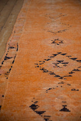 Angled view of the distressed hand-knotted texture on a saffron orange Kurd runner.