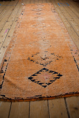 Angled view along the distressed Kurd runner, showing its tangerine texture and navy medallions.