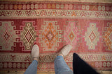 Vintage distressed Kurd runner featuring geometric medallions and floral vinery in raspberry, tangerine, ivory.