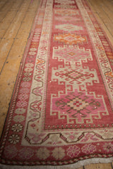 Distressed Kurd runner with raspberry red abrashed ground, intricate vinery, and hook motif.