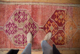 Distressed Kurd runner with magenta and wine primitive medallions on an abrashed raspberry field.