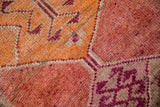 Primitive geometric pattern on distressed Kurd rug in raspberry, orange, and wine colors.