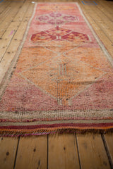 Distressed texture of vintage Kurd runner pile with raspberry pink, orange tones, and short fringe.