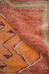 Distressed pile texture of a vintage Kurd rug in pale raspberry and saffron orange.