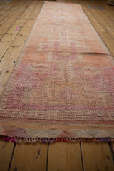 Distressed vintage Kurd runner showing short pile texture, fringed end, pink and orange tones.