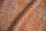 Folded vintage distressed Kurd runner, showing short pile texture and muted pink, orange hues.