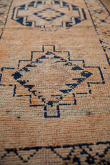 Distressed Kurd runner with visible knot heads and geometric navy patterns on pale orange.