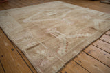 Vintage distressed Oushak rug corner, showing low pile, even wear, and light beige tones.