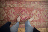 Kurd rug runner showcasing geometric pinwheel blossoms, an abrashed field, and distressed raspberry tones.