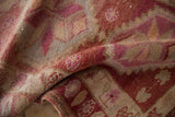 Folded vintage Kurd runner with distressed raspberry and ivory pile, faint foundation showing.