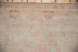 Distressed Oushak rug pile with blush and pale blue blossom border and even wear.