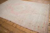 Softly faded Oushak rug corner, showing blush and platinum blossom border.
