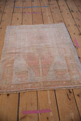Angled view of a distressed Oushak rug showing its faded prayer design in dusty rose and ivory.