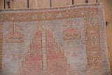 Worn texture at the top of a vintage Oushak prayer rug's dusty rose mehrab and border.