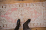 Distressed Oushak runner with dusty rose and ivory shield medallion and serrated spandrels.