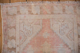 Distressed Oushak rug runner showing worn texture, muted pink, ivory, and blue tones.