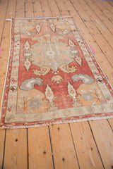 Distressed vintage Oushak rug detail: faded brick red field, pale sage cypress, floral border.