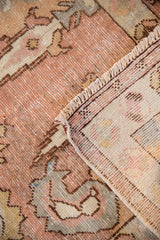 Close-up of hand-knotted vintage Oushak rug showing distressed texture with muted tones and cream fringe.