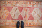 Distressed Kurd runner detail: raspberry and tangerine geometric medallions with starburst florals.