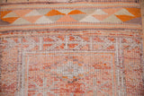 Distressed Kurd rug runner: tangerine geometric border and textured pile showing motifs.