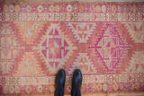Distressed vintage Kurd runner showing wear, geometric dusty reds, orange, and sand.