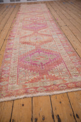 Distressed Kurd runner detail: geometric patterns in dusty raspberry, ivory, with even pile wear.
