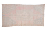 Distressed vintage Oushak runner with a faded medallion in soft pink, slate blue, and ivory.