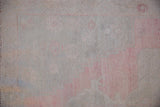 Texture of a distressed Oushak rug showing even wear across the pale pink and ivory knot heads.