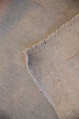 Corner view of a vintage Oushak rug showing the hand-knotted back and low, distressed pile.