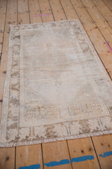 Textured vintage Oushak rug in ivory and faded brown, showing foundation wear.