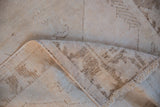 Worn ivory pile, exposed foundation, and fringe detail on vintage distressed Oushak rug.