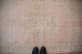 A view from above showing the distressed Oushak rug's low pile and time-softened mauve and sand tones.