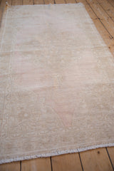 Lengthwise view of a distressed Oushak runner highlighting its faded pattern in dusty mauve and beige.