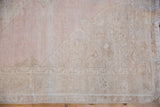 Hand-knotted texture of a distressed Oushak runner showing mostly even wear in mauve and sand.