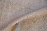 Close-up of the distressed Oushak rug's low pile, showing even wear to the knot heads in soft mauve and beige.