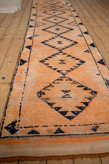 Distressed tangerine orange Kurd runner, navy primitive diamond motifs, visible knot heads.