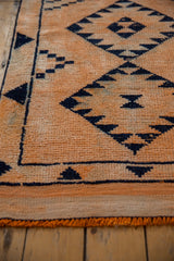 Distressed Kurd runner featuring tangerine orange field and navy diamond serrated floral gul motifs.