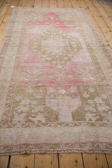 Close-up of distressed Oushak runner's texture, revealing heavy abrashes, pink, and coffee brown floral motifs.