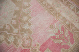 Distressed vintage Oushak rug texture, with faded pink, coffee brown, and pale blue floral design.
