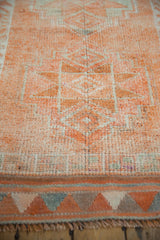 Textured short pile of a distressed Kurd runner, showing tangerine, ivory abrash patterns and fringed end.