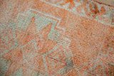 Textured short pile of a distressed Kurd runner with tangerine abrash and geometric silver pattern.