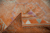Distressed tangerine, ivory, fuchsia pile texture with woven striped selvage of Kurd rug.