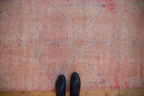 Distressed Kurd runner's pink and melon pile texture, visible knot heads, shown with shoes.