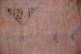 Distressed blush and pink Kurd rug pile, revealing knot heads and geometric triangle details.
