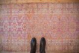 Distressed vintage Kurd rug close-up, fuchsia geometric guls, tangerine and beige tones.