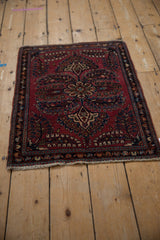 Fringed corner of a vintage Sarouk rug with raspberry red field and navy blue floral border.