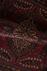 Vintage Sarouk rug's raspberry red pile, revealing navy blue and blush floral blossoms.